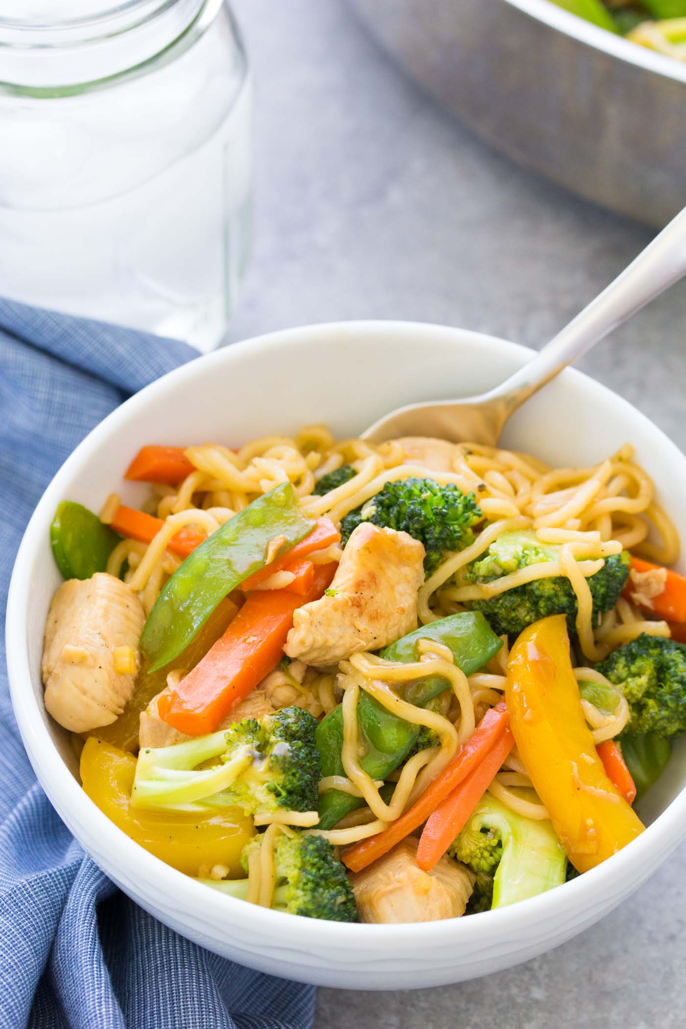 Teriyaki chicken and vegetables with noodles served in a bowl with a fork.