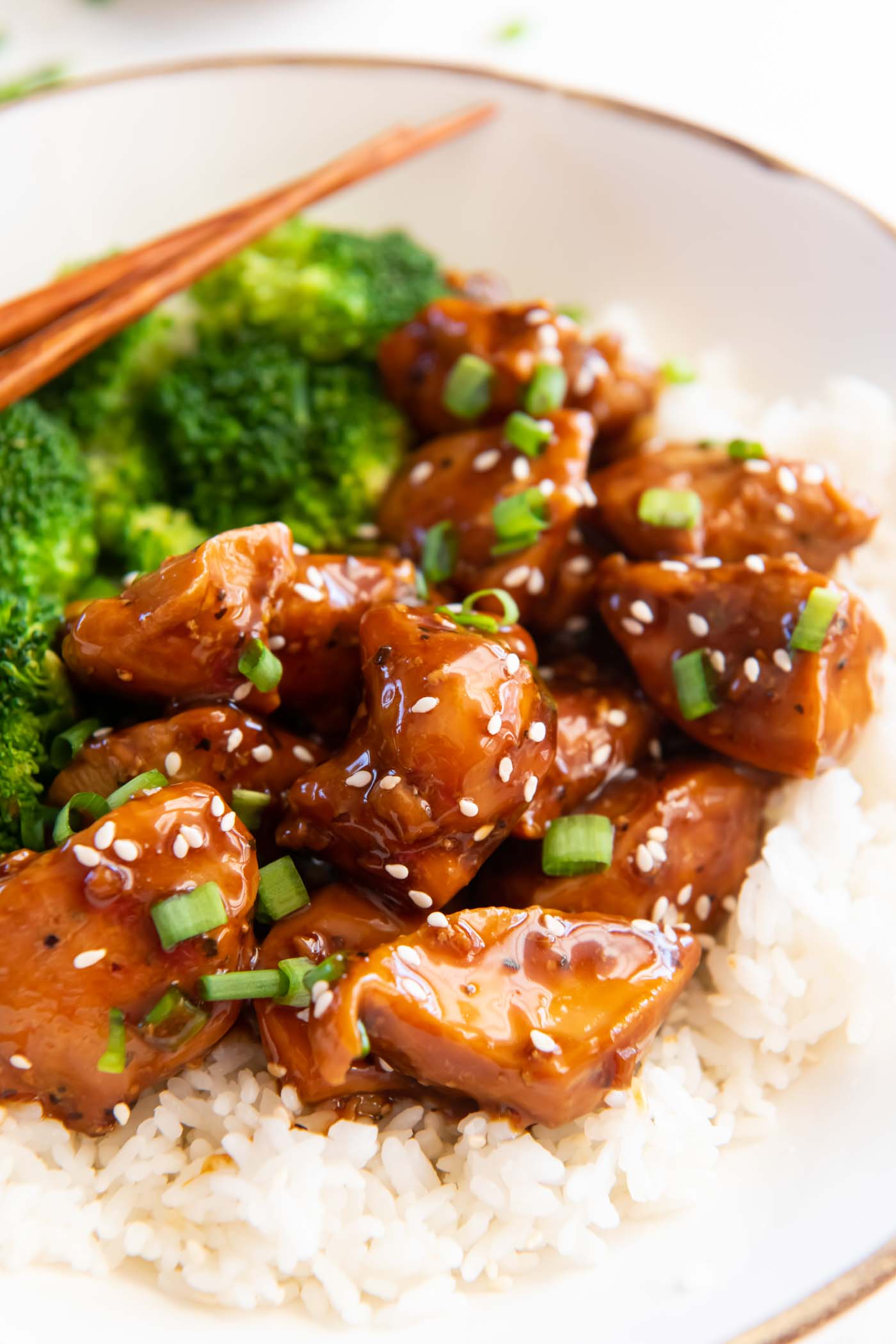 Teriyaki chicken served with white rice, broccoli, sesame seeds and green onions.