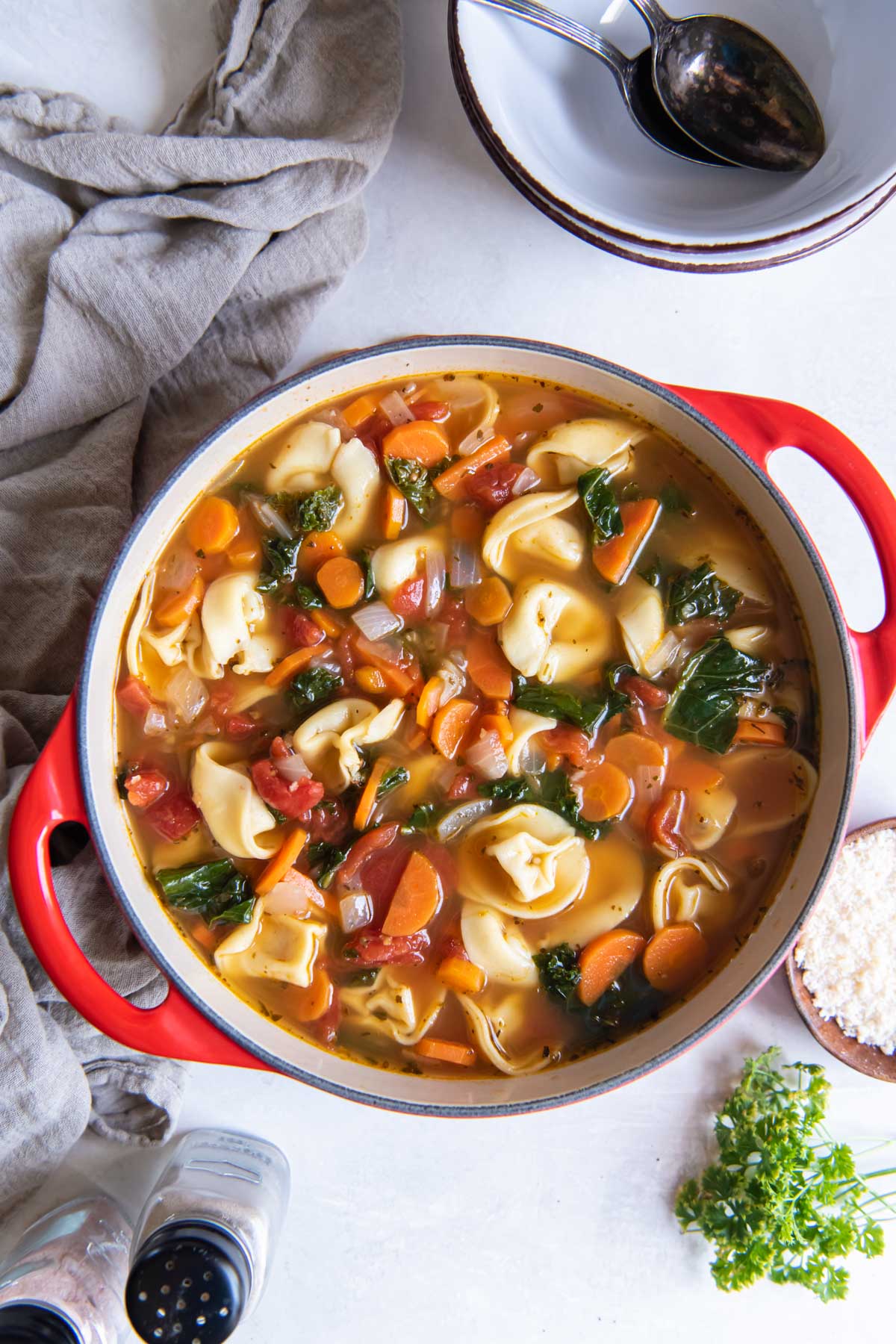 Tortellini soup with kale in red Dutch oven pot.