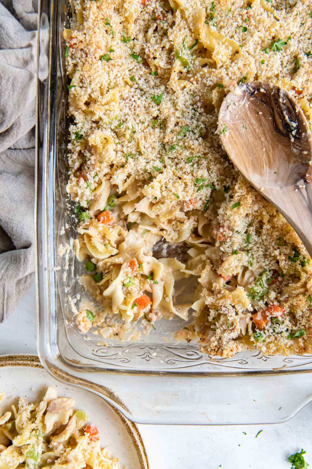 Tuna casserole in a baking dish with a wooden spoon.
