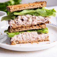 Two tuna salad sandwich halves with lettuce stacked on top of each other.