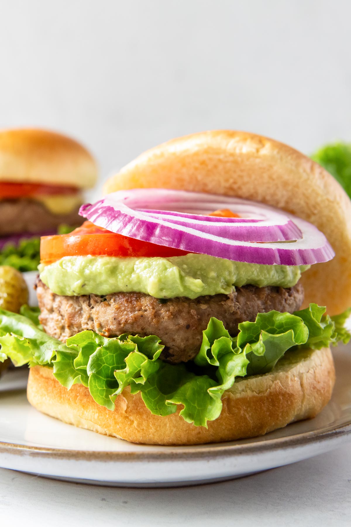 turkey burger served on a bun with lettuce, guacamole, tomato and red onion