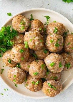 Baked turkey meatballs on a plate with parsley garnish.