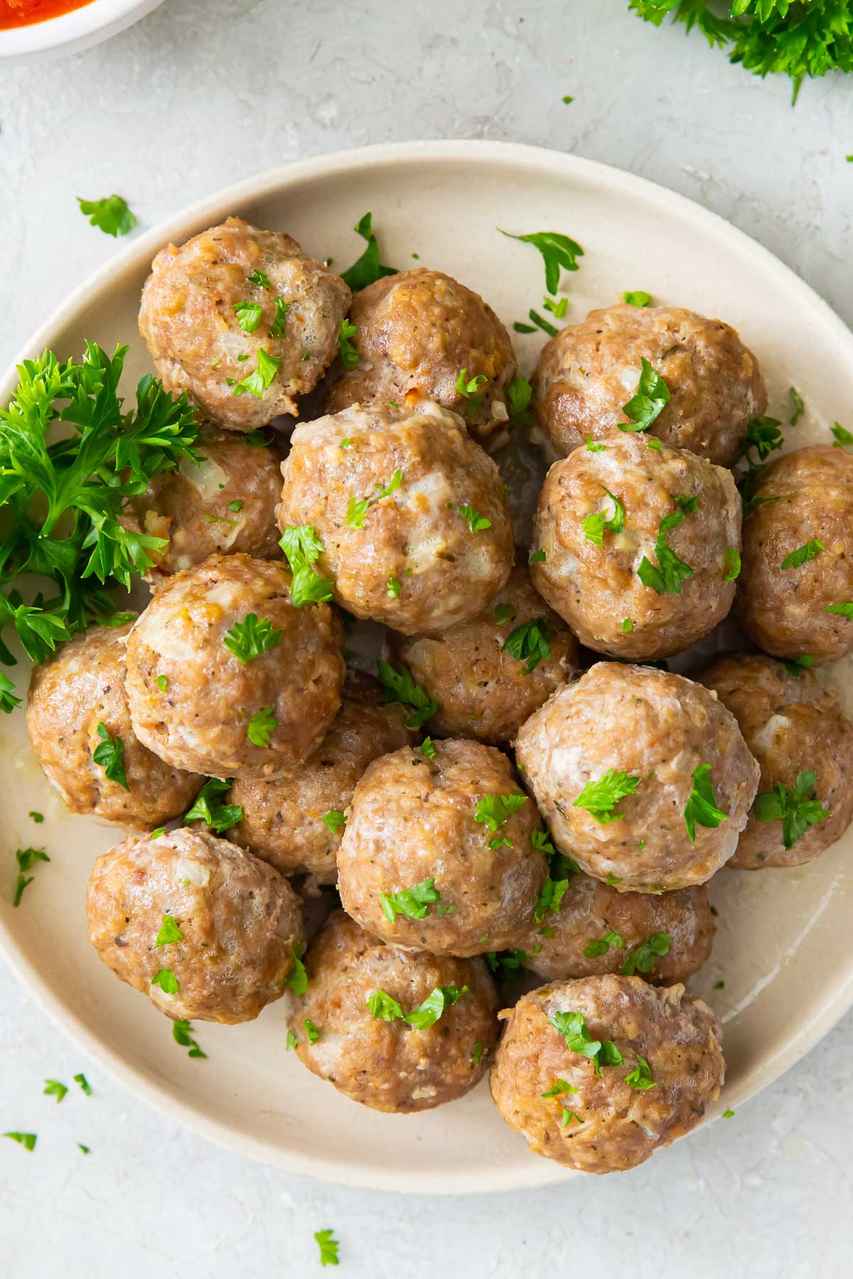 Baked turkey meatballs on a plate with parsley garnish.