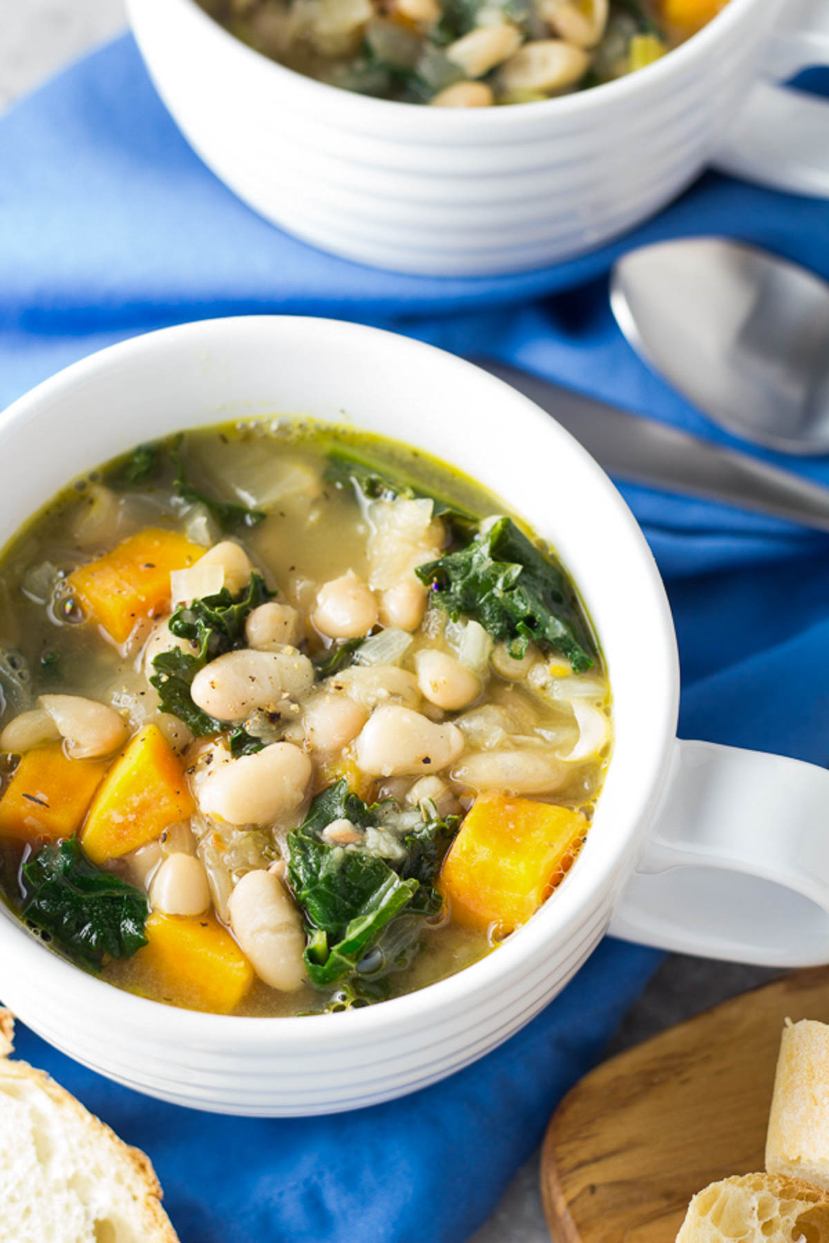 White bean soup with kale and sweet potatoes served in soup bowls. 