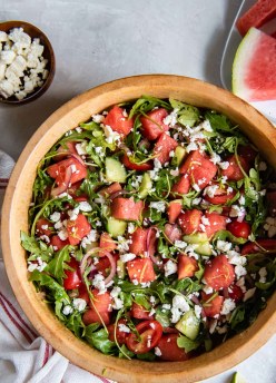 Watermelon salad with arugula and feta in a wood serving bowl.