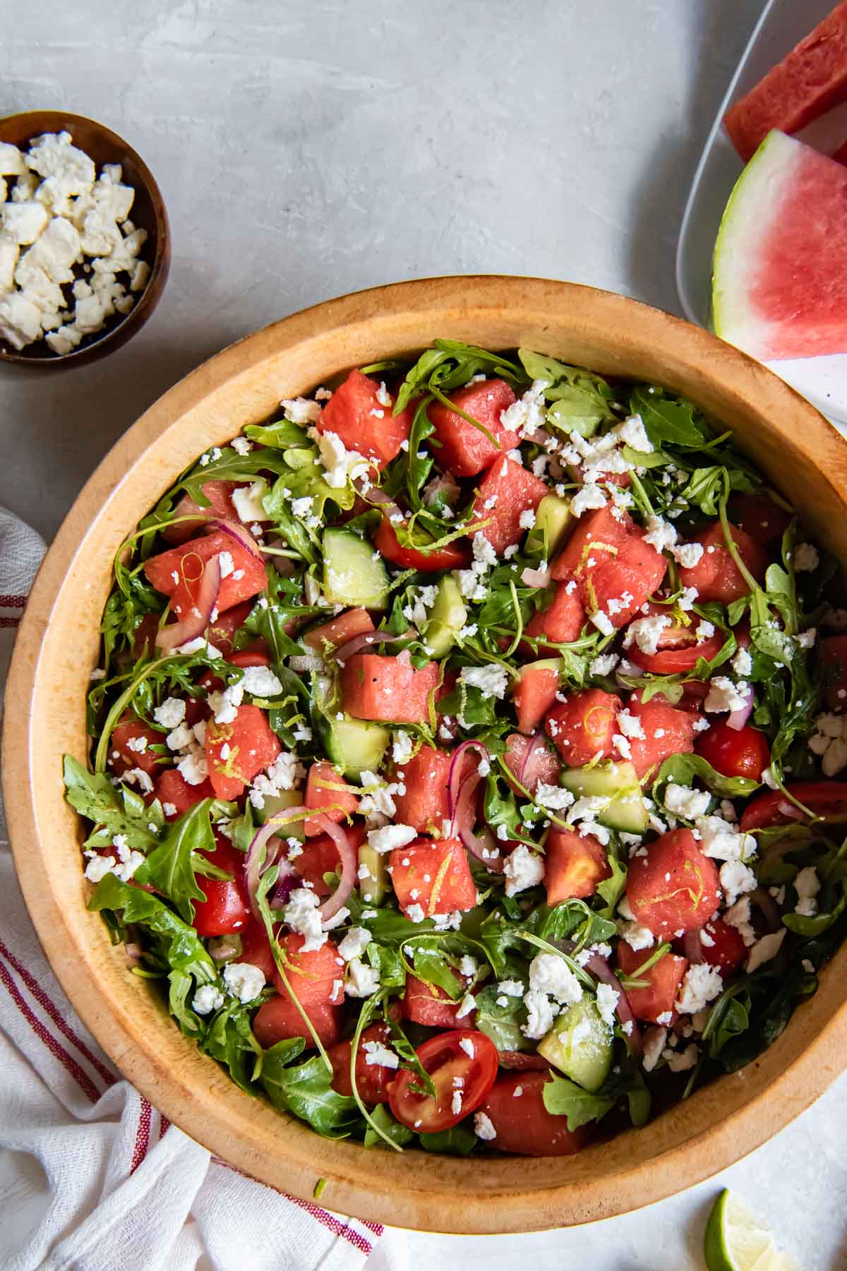 Watermelon salad with arugula and feta in a wood serving bowl.