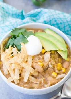 Slow cooker white chicken chili with toppings in bowl.