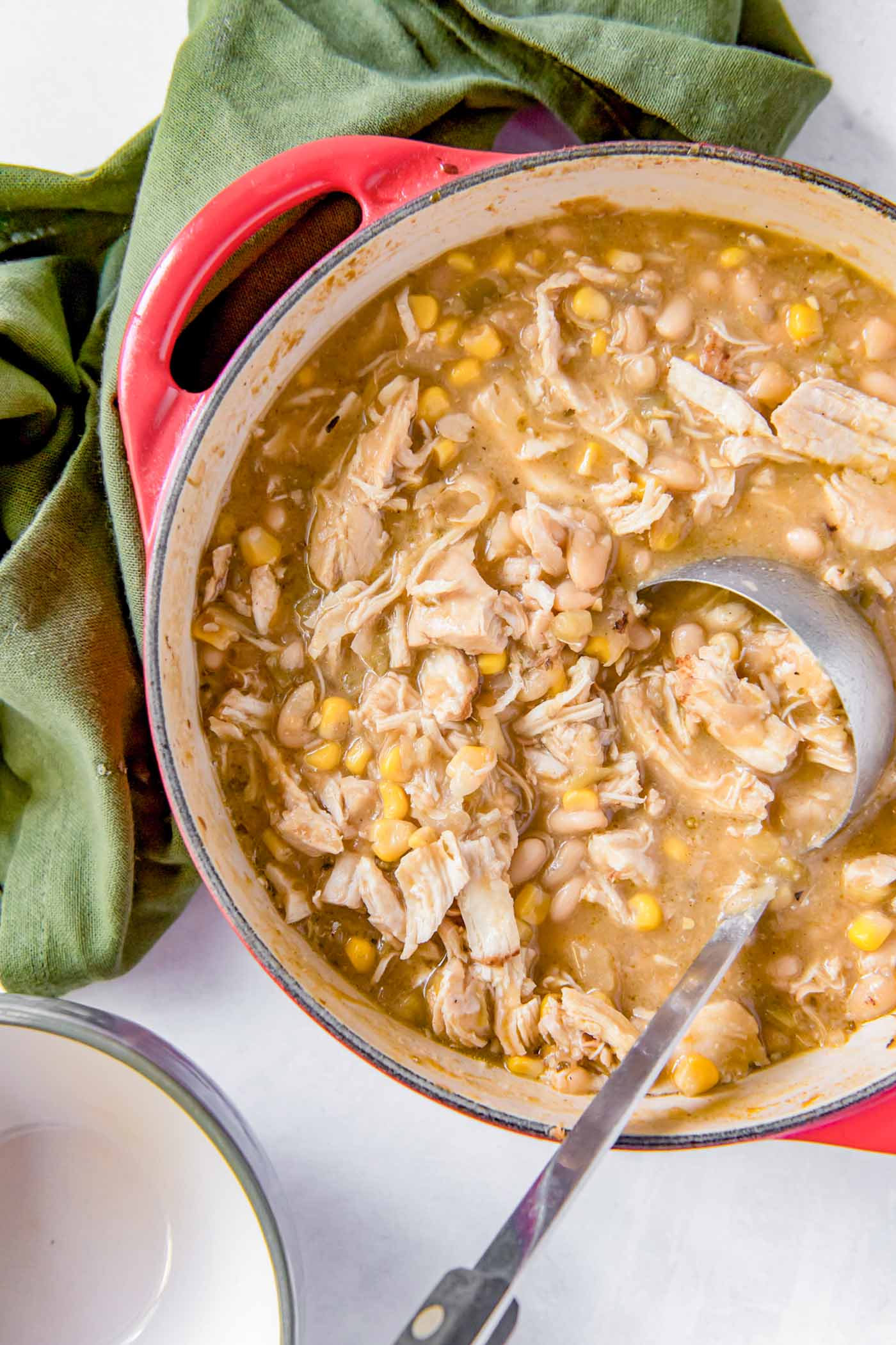 White chicken chili in a dutch oven pot with a ladle.